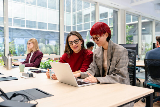 Women collaborating on laptop in modern coworking office