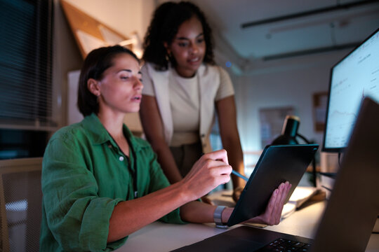 Two women collaborate on a project using technology.