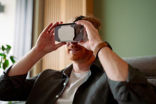 Man uses smartphone for virtual reality experience in modern room
