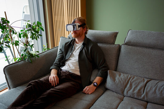 Man using virtual reality headset while sitting on a couch indoors
