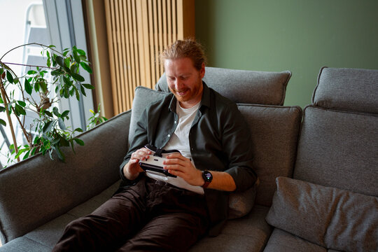 Man using a device on a couch in a modern living room
