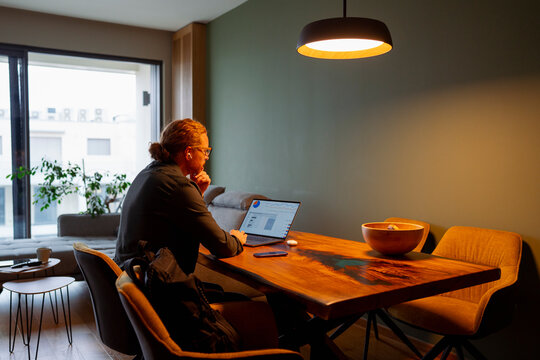 Person works on laptop at wooden table in a modern indoor setting
