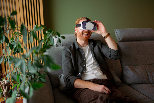 Man using virtual reality headset while sitting on a couch
