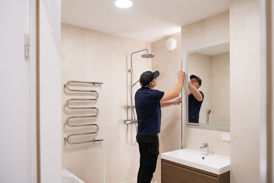 Worker Installs Mirror in Modern Bathroom During Daylight