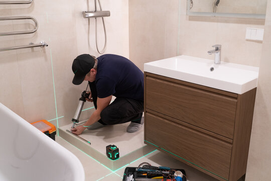 Worker Installing Bathroom Fixtures in a Modern Setting