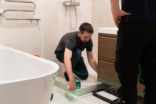 Men Working on Shower Installation With Laser Level And Meter