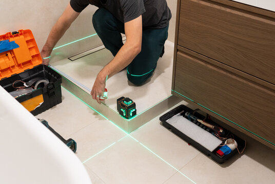 Worker Uses Meter And Laser Level Before Shower Installation