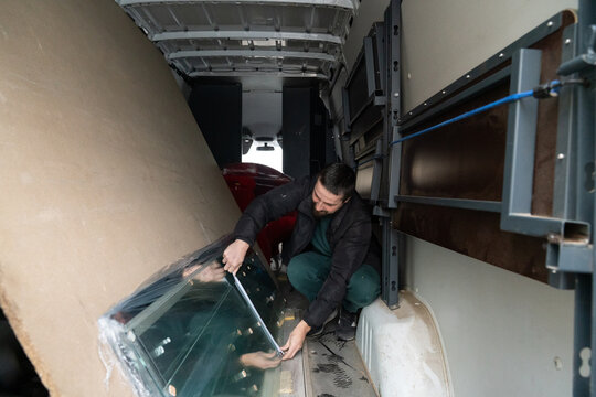 Man Measuring Glass Panel Into Delivery Van 