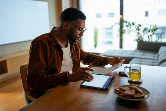 Man at table with snacks, tablet
