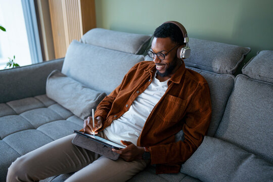 Guy on couch with tablet, headphones
