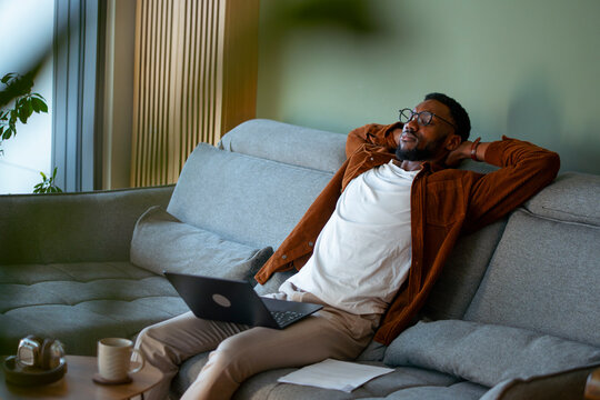 Man relaxing on couch while using laptop
