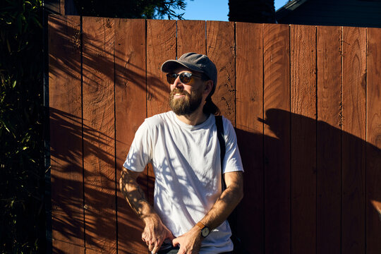 Happy man leans against the wooden fence