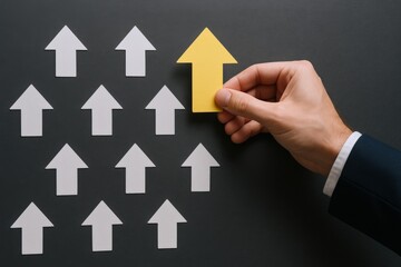 Hand placing yellow arrow among white arrows pointing up, symbolizing leadership and business growth