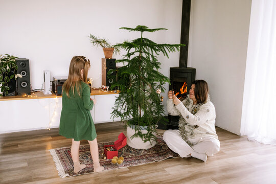 A woman and a child are decorating a Christmas tree.