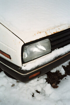 Front headlight of a white car during winter