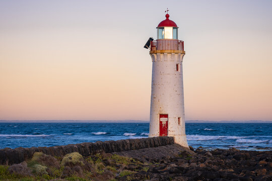 Pre dawn glow behind a white coastal lighthouse