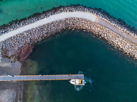 Small boat idling at a jetty inside a breakwater