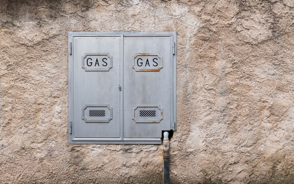 Metallic gas utility cabinet on a textured stucco wall.