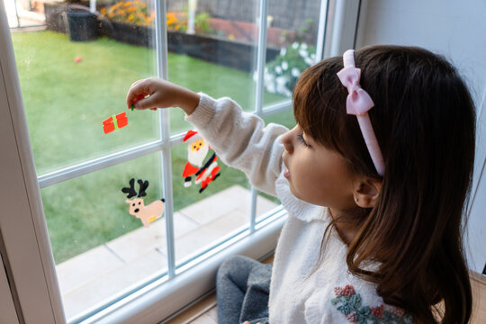 Young girl decorating window with Christmas holiday stickers
