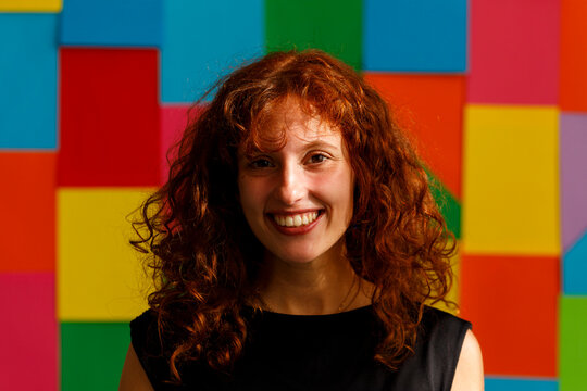Woman Smiles in Front of Colorful Wall