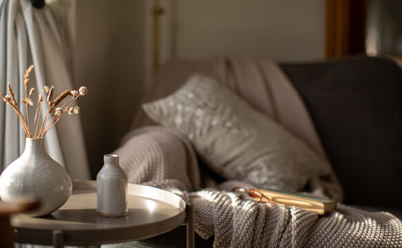 Cosy indoor scene with dried grasses in a sunlit vase.