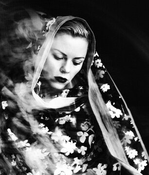 Woman in floral headscarf with dark background