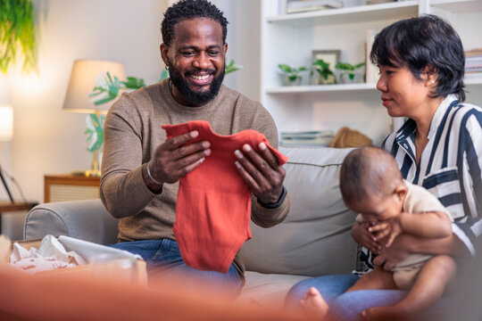 Parents admire baby clothes with their infant.