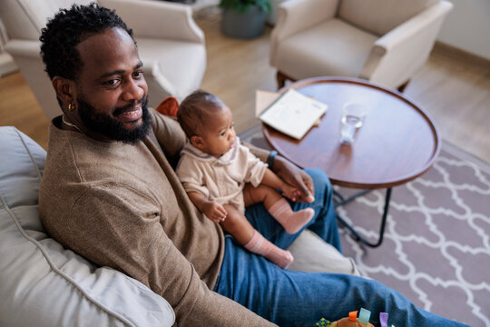 Father and baby relax together on a comfortable sofa.