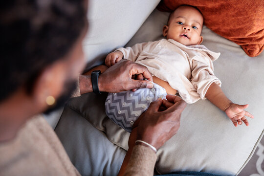 Father changing baby's diaper on couch.