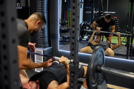 Two men lift weights in gym during workout session