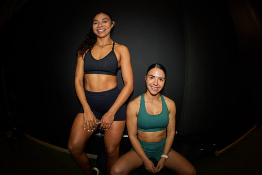 Women posing together in fitness attire in a gym setting