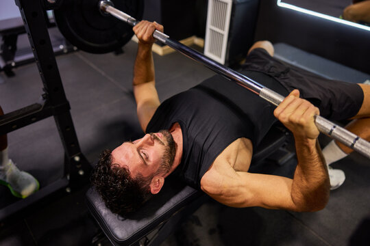 Man lifts weights at gym during workout session with barbell