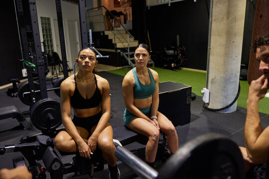 Women discussing workout plans in gym during evening session