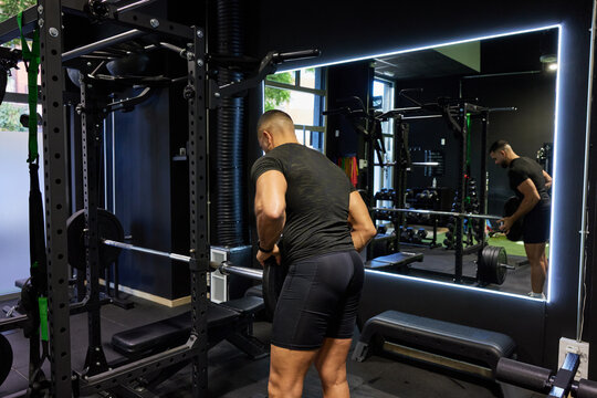 Man lifts weights in gym during workout session in evening time