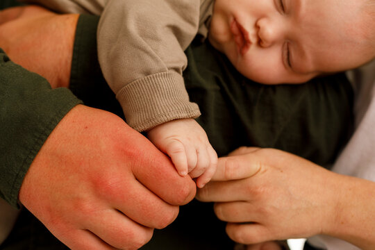 Family Members Hold Hands With Baby 