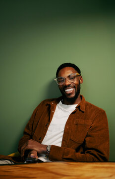 Man smiling in a room with green wall
