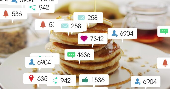Pouring syrup over stack of pancakes with banana at breakfast table, showing social notifications