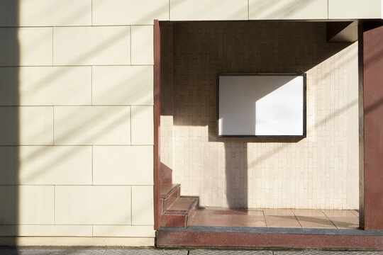 Bright Yellow Wall with a Blank White Poster on a Sunny Day