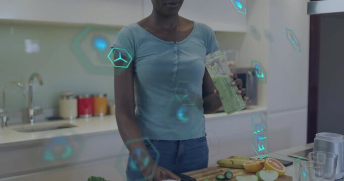 Woman removing lid tasting green shake checking health in kitchen, teal hex icons floating near cup