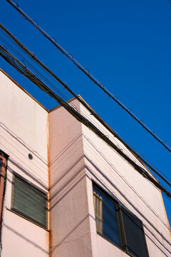 Building Corner With Power Lines Against Blue Sky on a Sunny Day