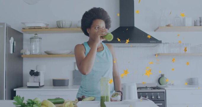 Woman raising glass tasting green smoothie in kitchen testing for health while stars cross torso