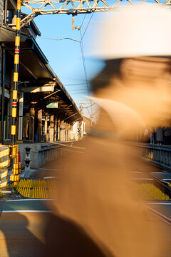 Train station with a blurred person walking in front of the tracks. 