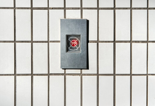 Red Stop Button on Tiled White Wall 