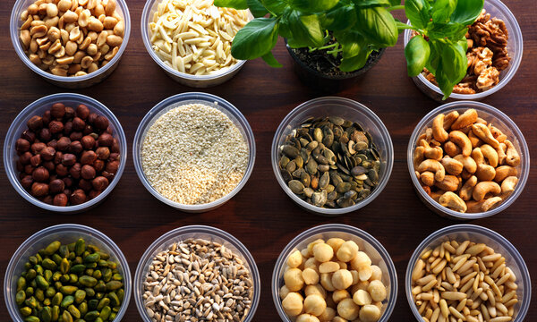 Variety of nuts and seeds arranged in clear bowls on wooden surface