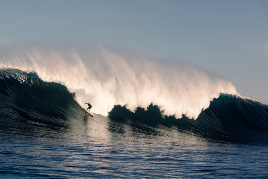 Surfer gliding a massive wave while practicing in harsh conditions