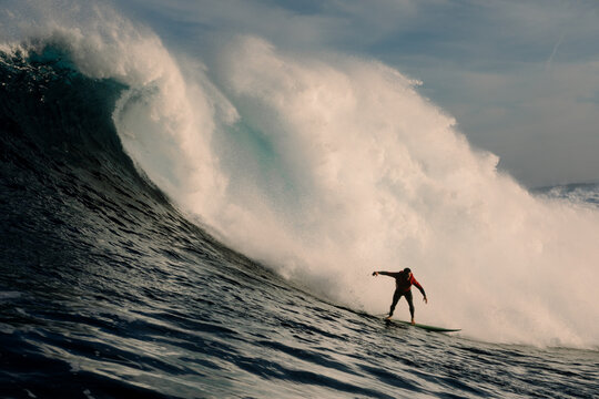 Surfer gliding across a massive open-sea wave