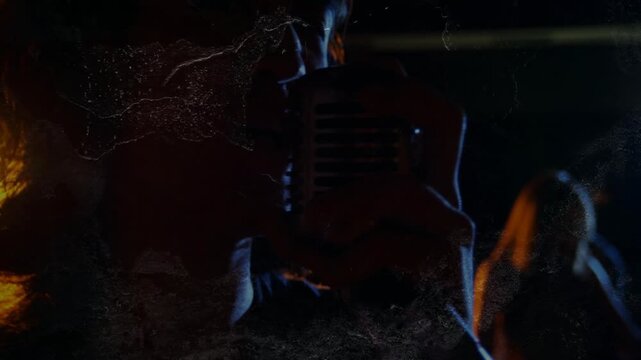 Hand reaching and vocalist bringing vintage mic closer, performing song under warm backlight haze