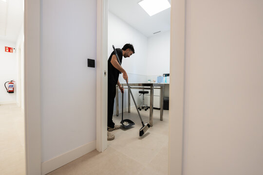 Hospital staff sweeping floor in veterinary clinic room