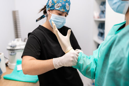 Veterinarian assisting colleague putting on surgical gloves