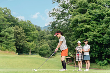 Obraz premium A woman playing golf on a golf course and a female golfer watching her swing